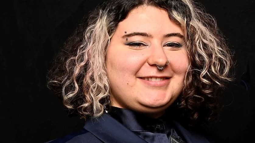 Portrait of Kira Scala in a blue blazer smiling at the camera