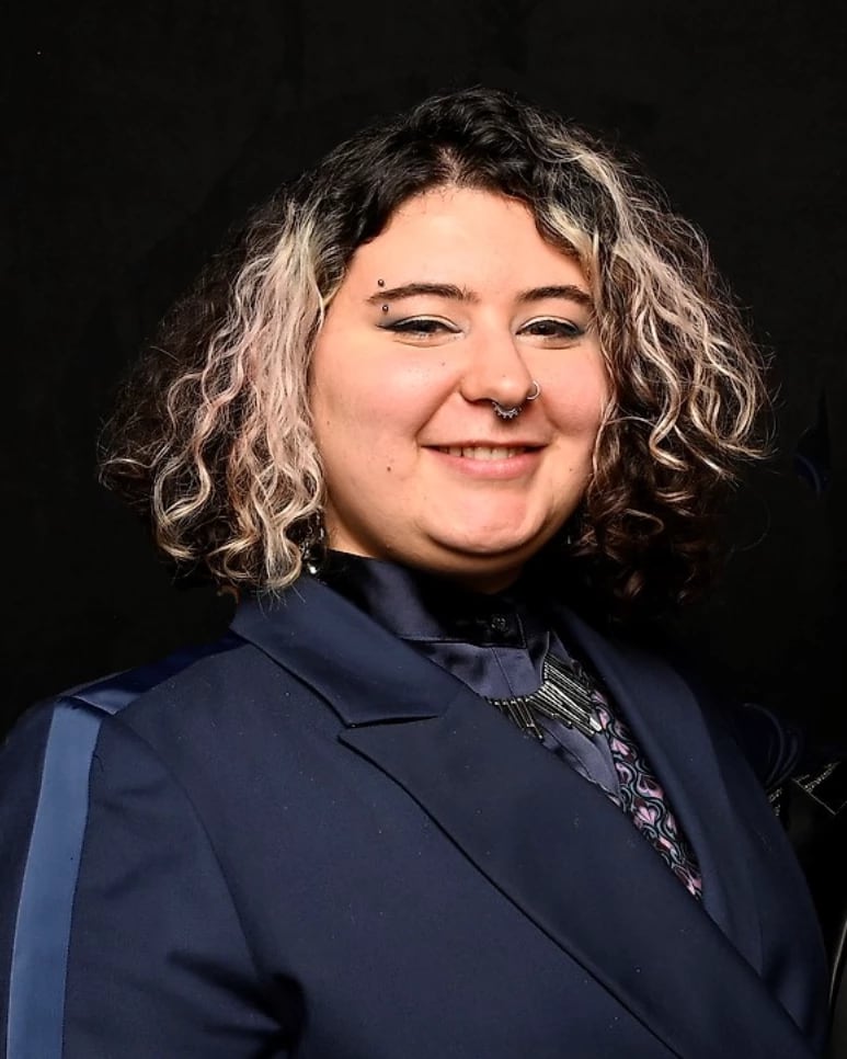 Portrait of Kira Scala in a blue blazer smiling at the camera