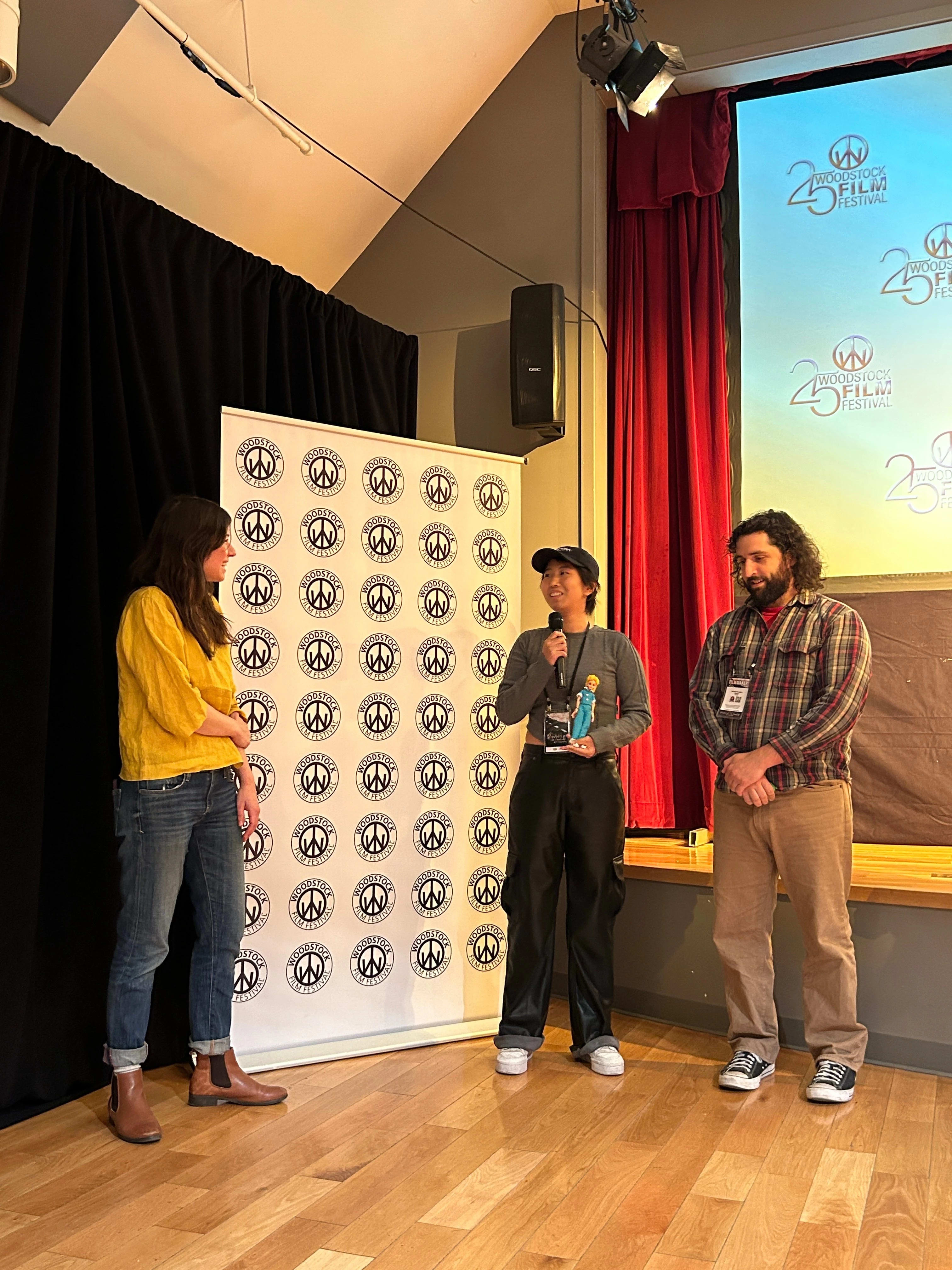 Three people stand at the front of a room giving a Q&A
