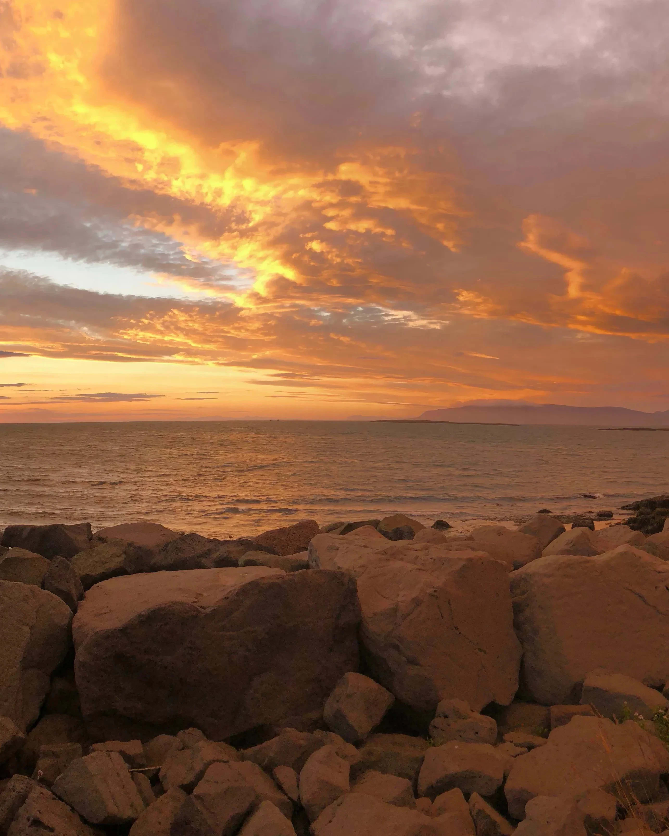 rocks in front of ocean with orange sky