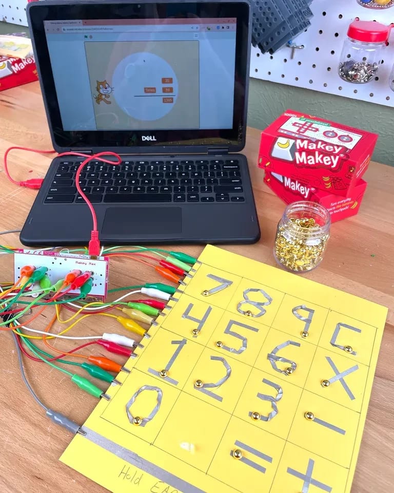 A yellow page with numbers attached by wires to a laptop.