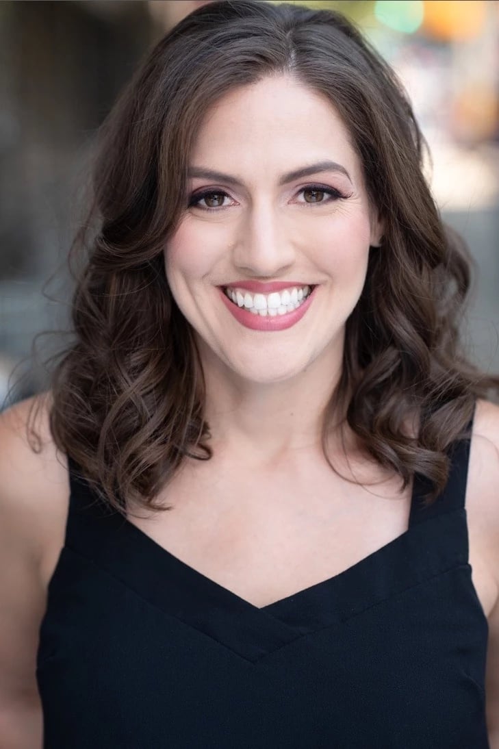 A photo of a woman from the shoulders up. She has long brown hair and is smiling.