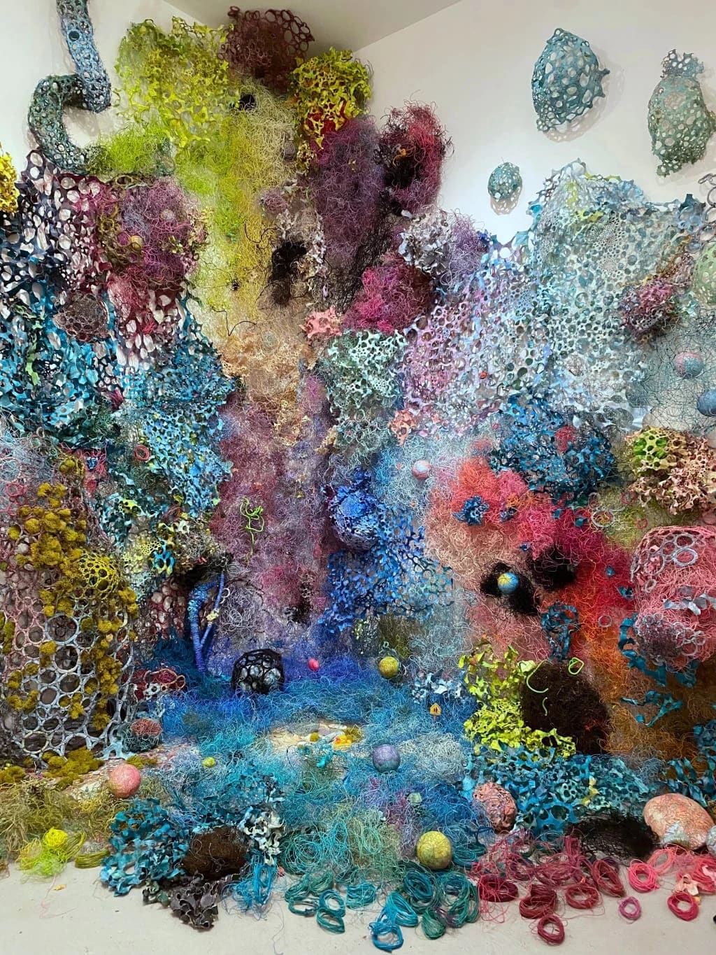 Mixed media, including cotton-covered wire, acrylic, maps, clay, paper, encaustic, styrofoam, moss, branches, found toys, ceramics, and debris