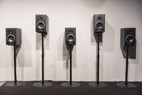 speakers on stands lined up against a blank wall