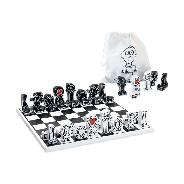 A chess set with black and white pieces made of Keith Haring's signature characters, set up to play