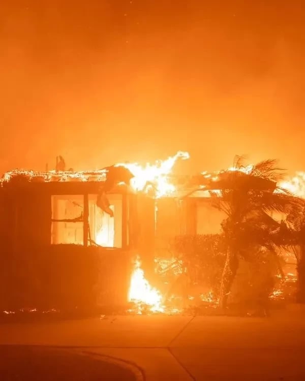 A house ablaze at night, flames consuming the structure, illuminating the dark surroundings with a fiery glow.