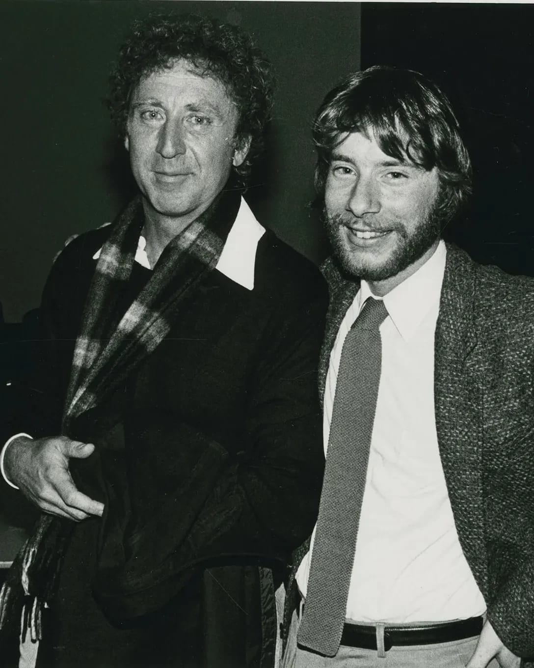 A black and white photo of two people posing and smiling next to each other.