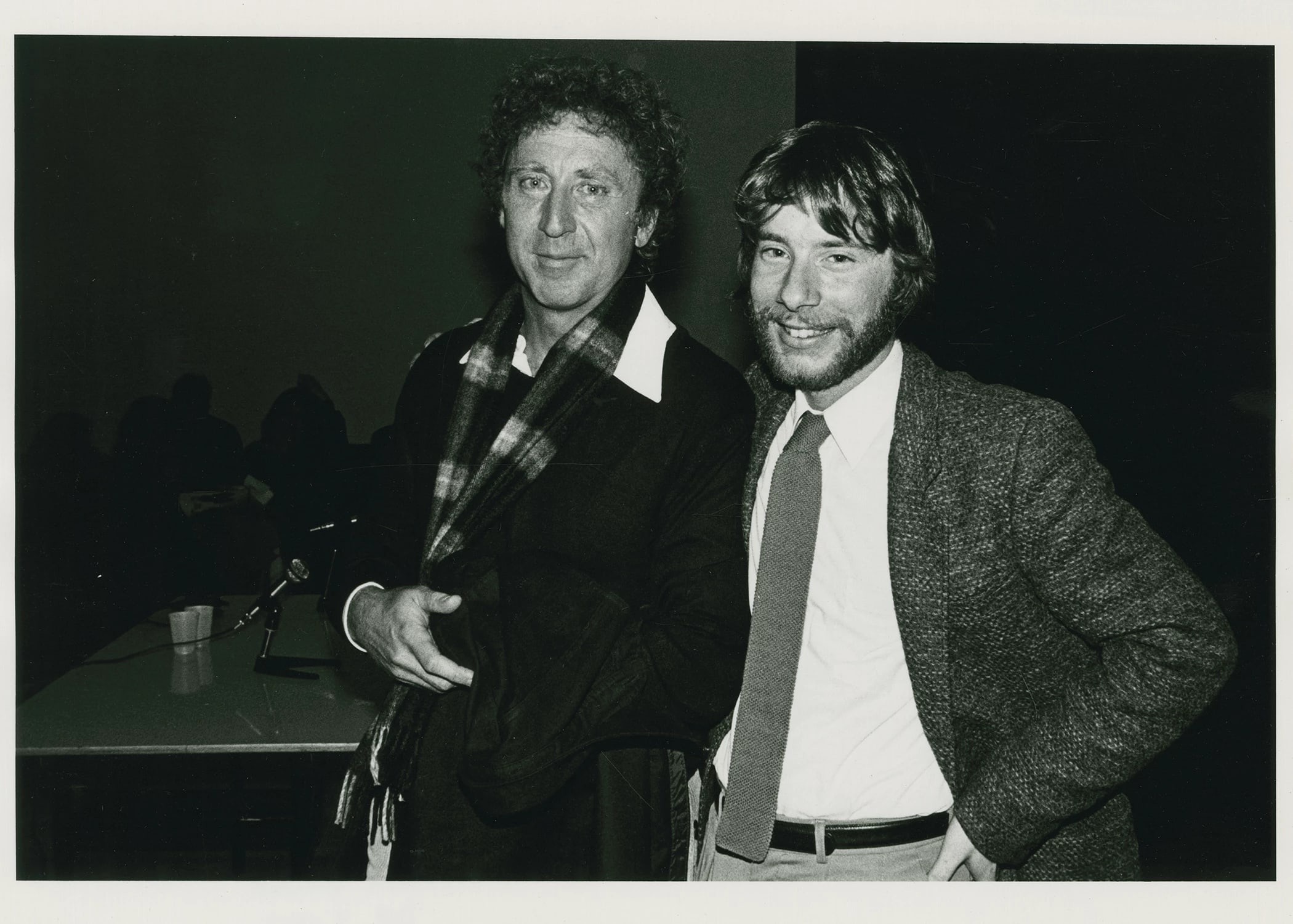 A black and white photo of two people posing and smiling next to each other.