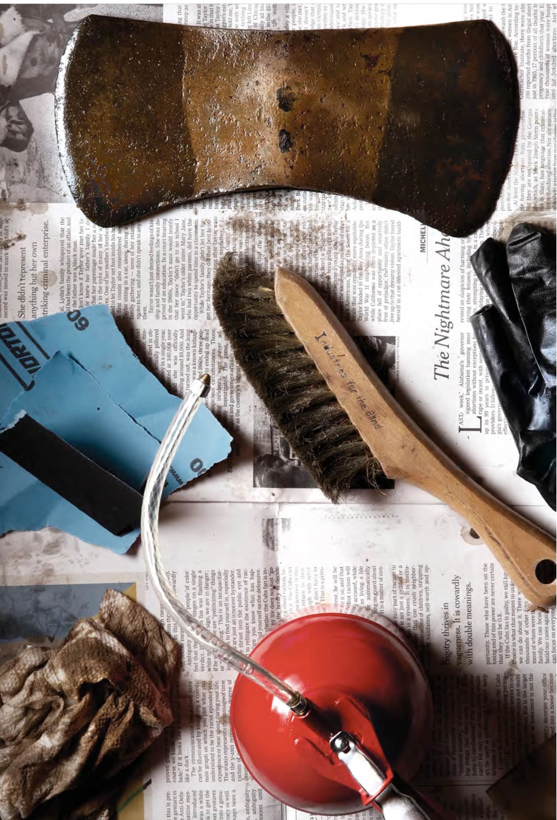 A collection of tools and miscellaneous items arranged on top of a newspaper, showcasing a cluttered workspace.