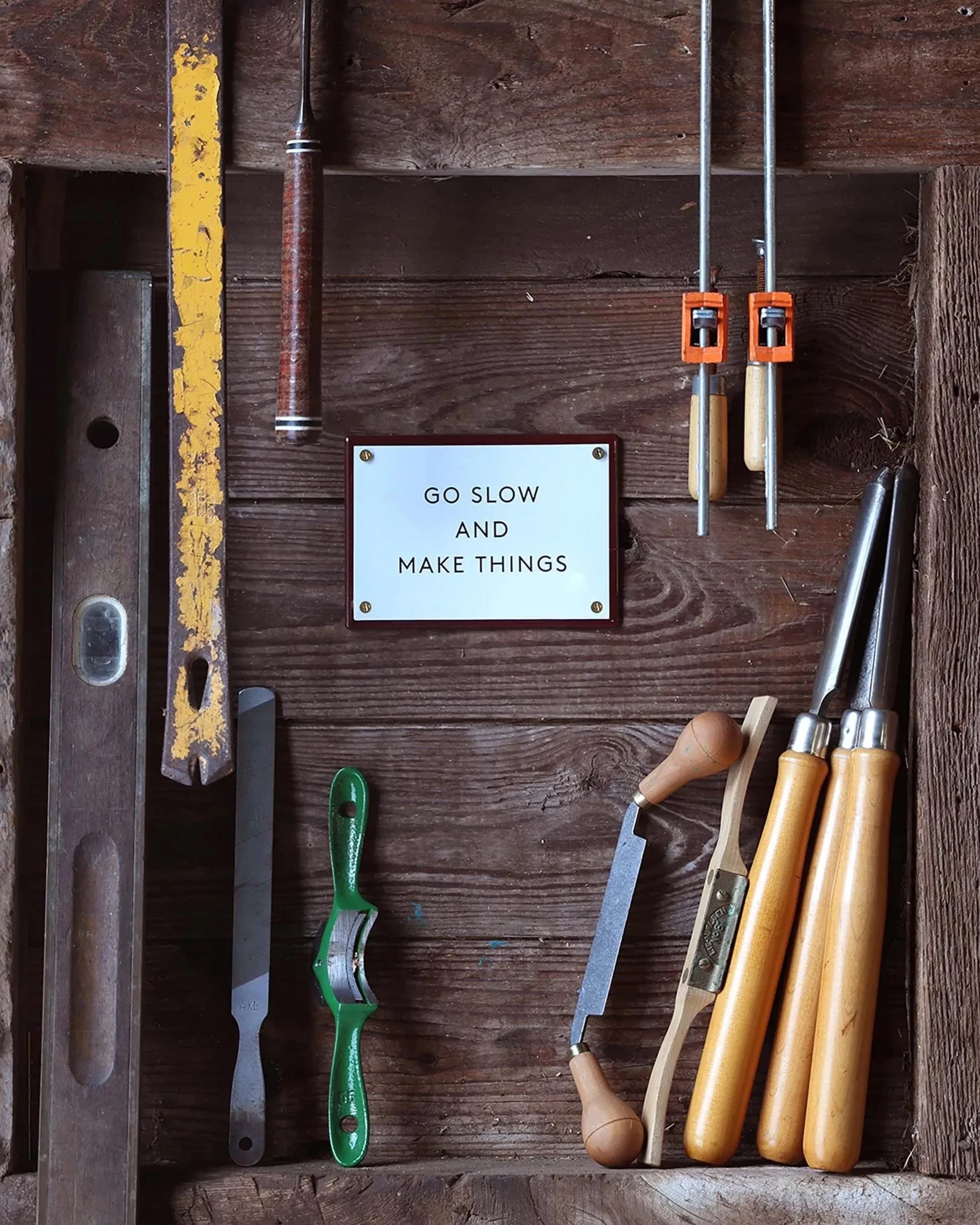 A wooden box featuring a sign that reads "go slow and make things," inviting creativity and craftsmanship.