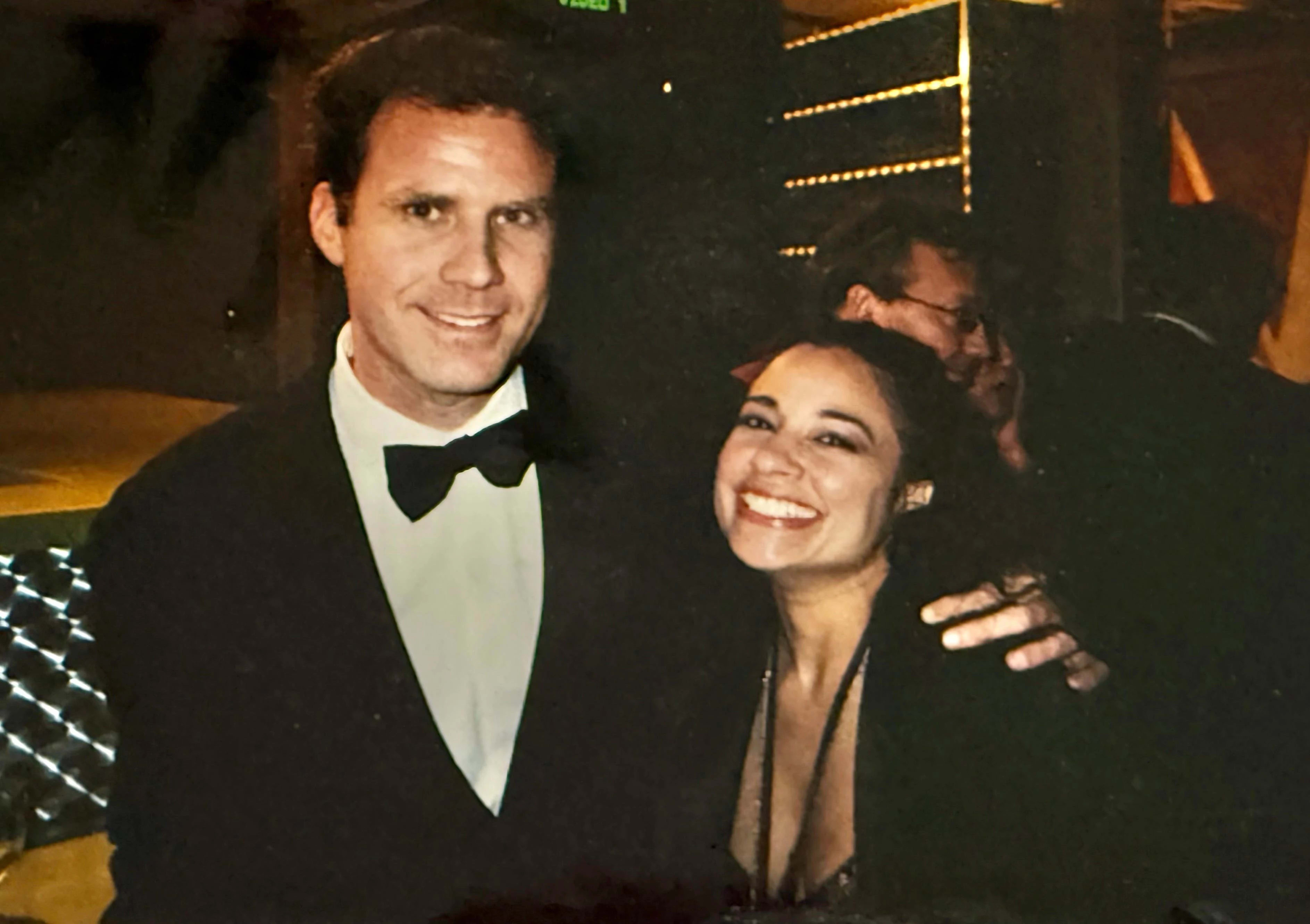  A man and woman stand side by side, smiling for a photo at an event, showcasing their stylish outfits.