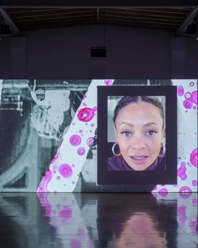 Projected screen depicting a woman's face as well as other shapes and images in the composition around her.