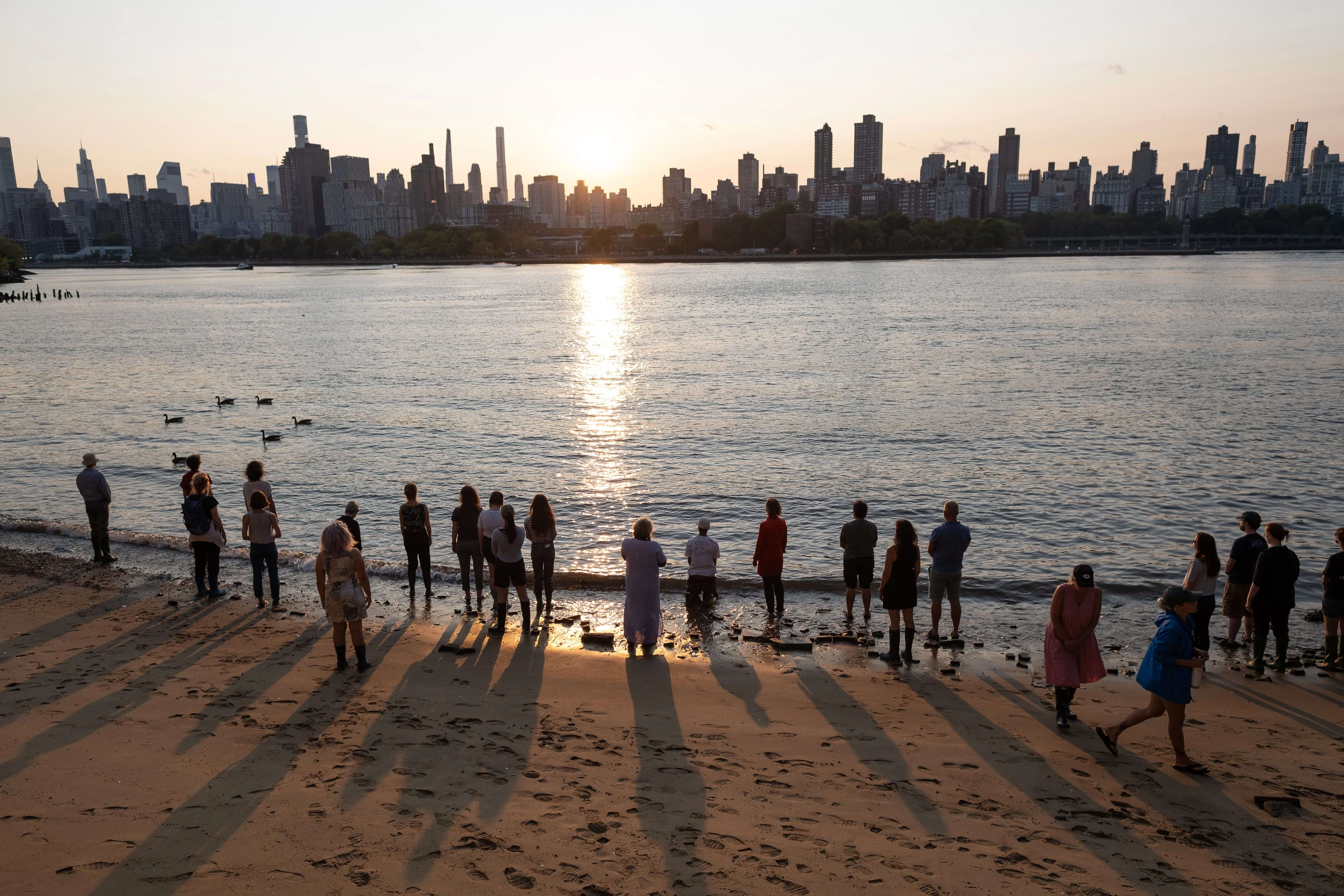 People standing along the beach looking at skyline 