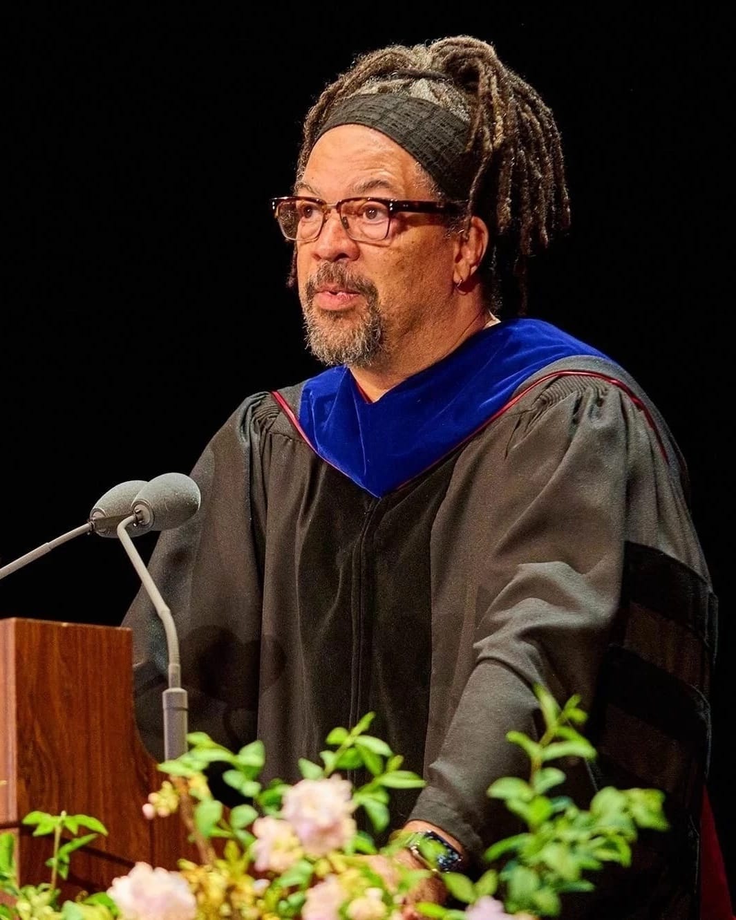 Commencement speaker Gary Simmons speaking on a podium decorated with flowers and the SVA logo
