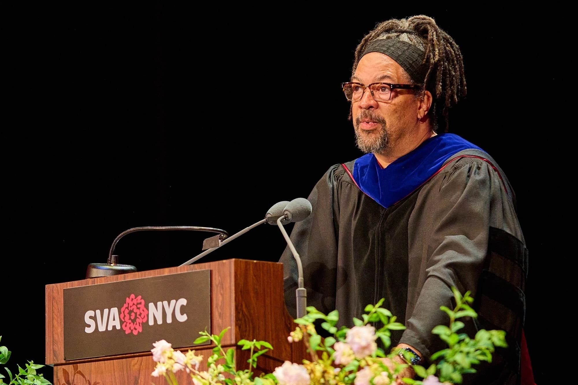 Commencement speaker Gary Simmons speaking on a podium decorated with flowers and the SVA logo