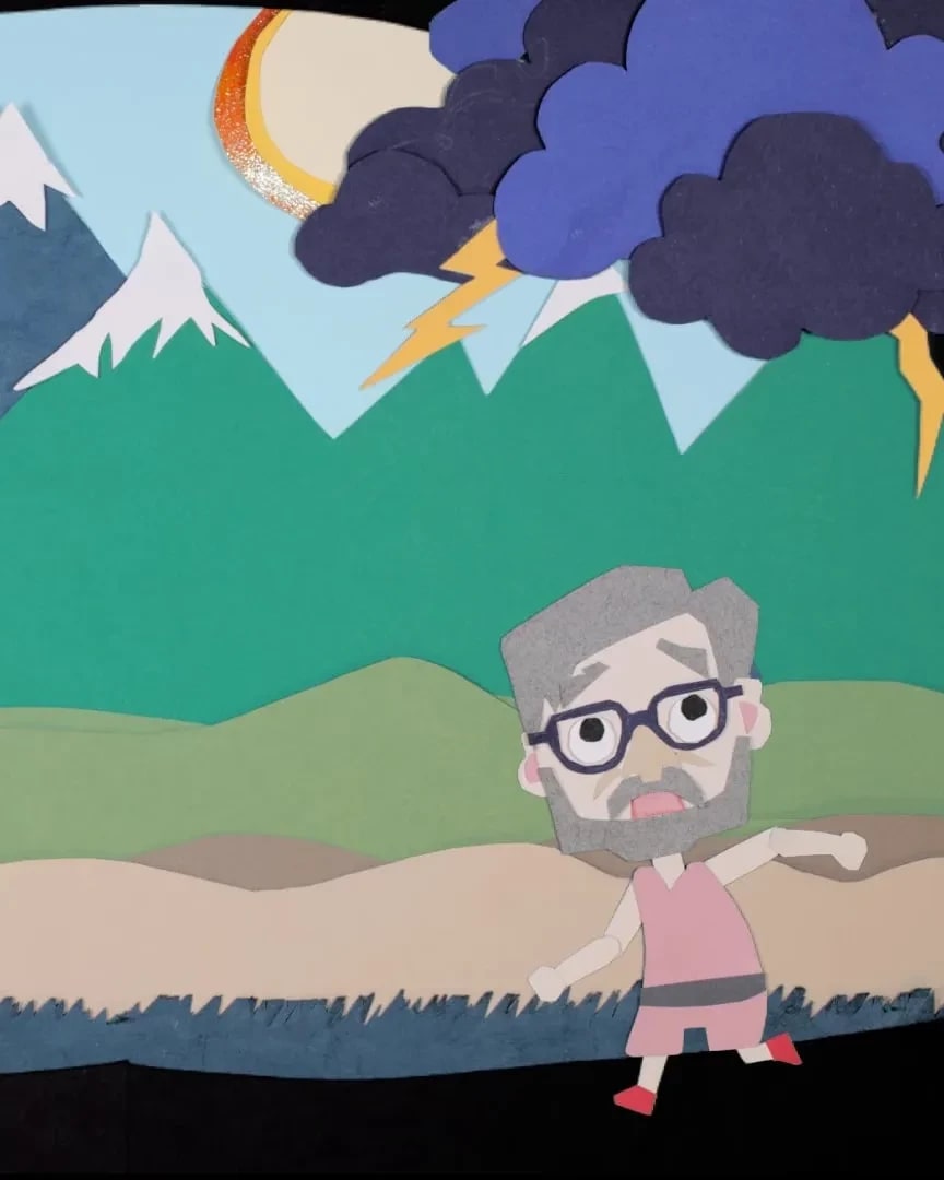 A paper depiction of an old man in front of a landscape while a storm thunders above him.