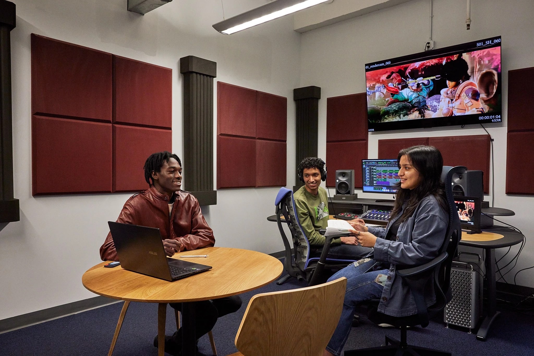 three people in front of an audio mixing board and display