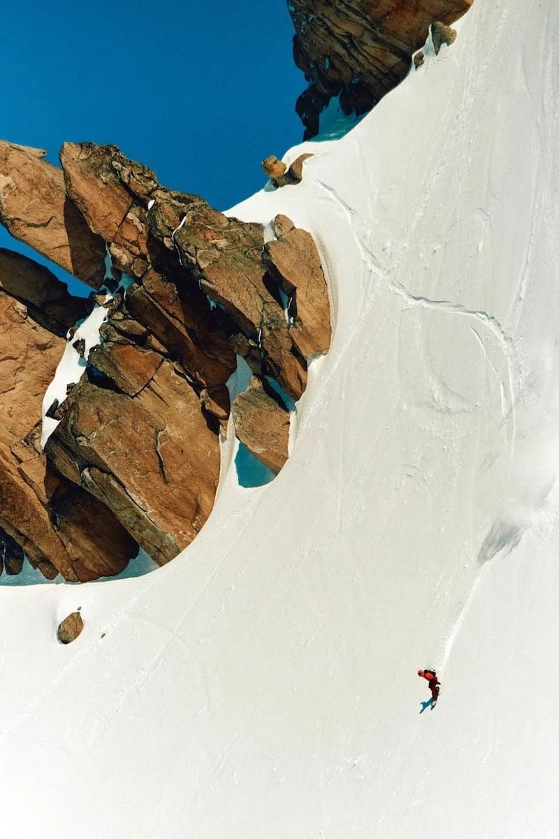 A skier descends a snow-covered mountain, showcasing their skill against a backdrop of pristine white slopes.