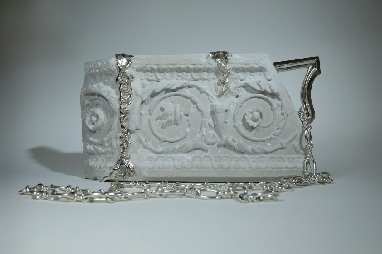 A piece of engraved porcelain with a chain draped on top of it