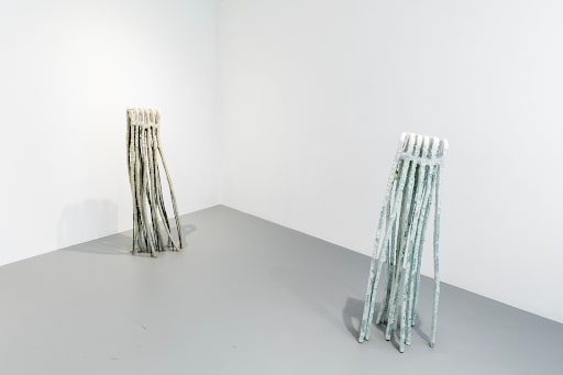 Two sculptures resembling bundles of sticks
