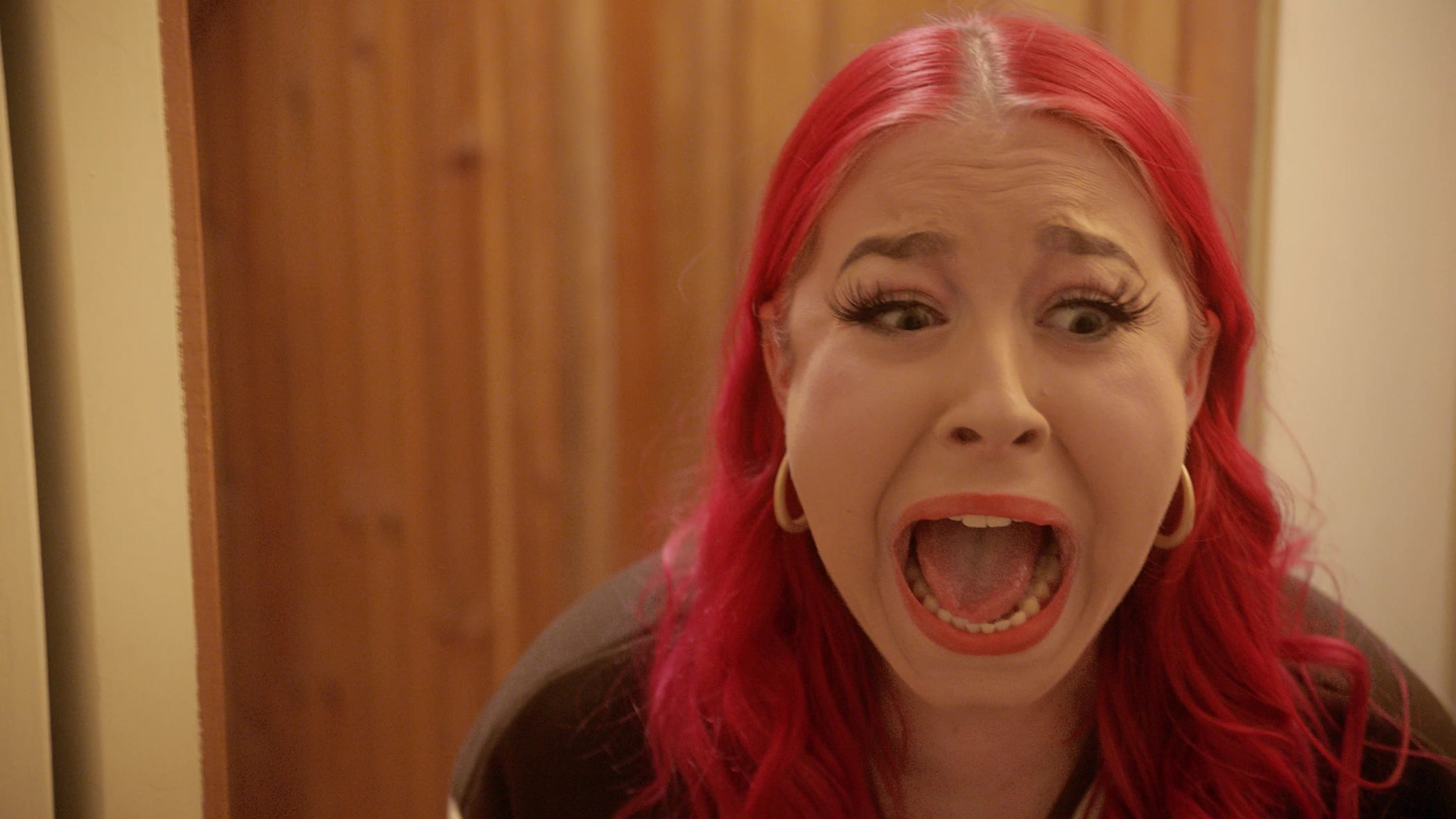 Close up of a girl with pink hair screaming in horror. 