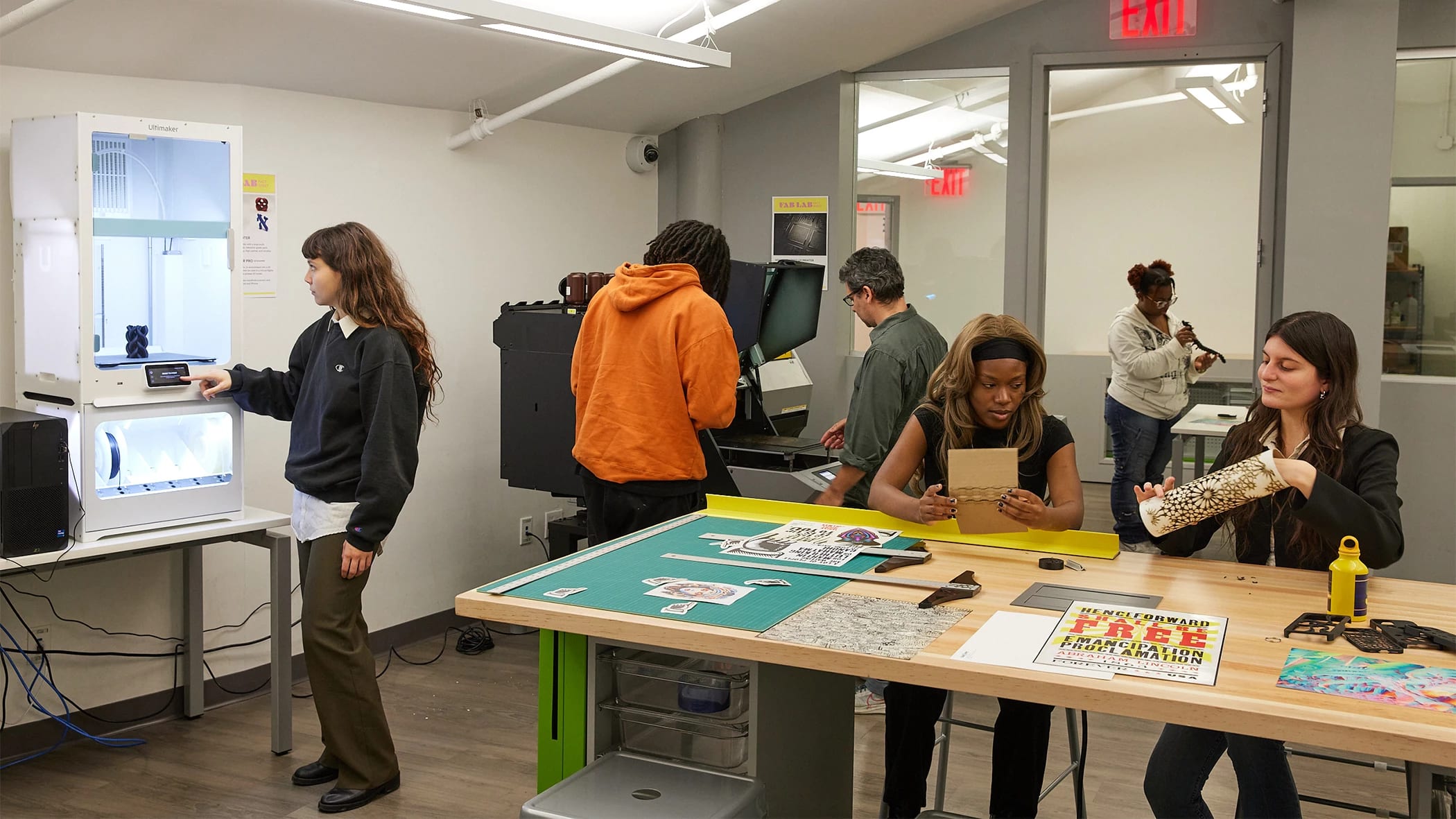 Students and instructors working on various projects in a design fabrication lab.