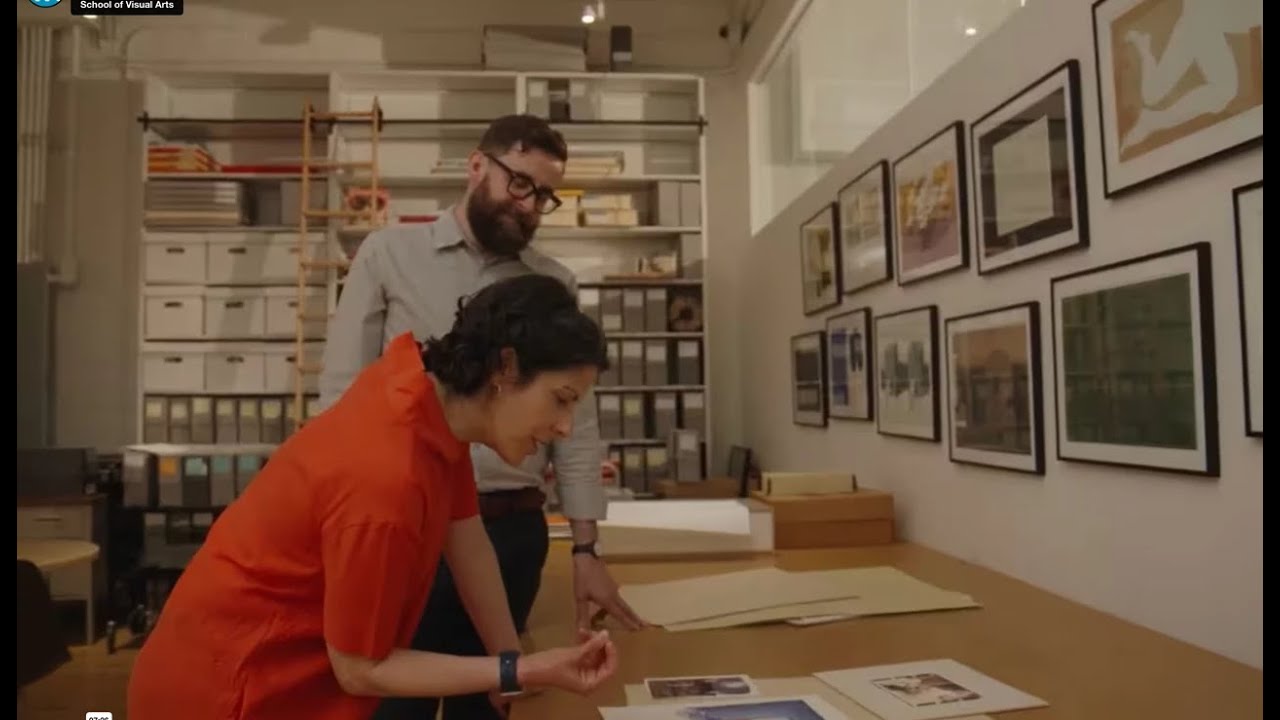 Two people in an office looking at a piece of ephemera on a desk